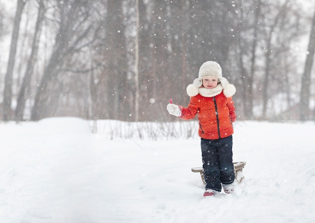 a little girl in a fluffy hat walks on a snowy winter day