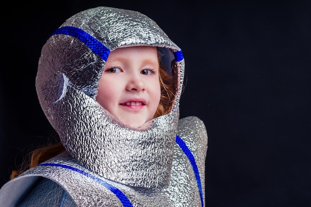 Little girl in foil diy space suit on a black background in the studio July 20, 1969 day of landing on the moon, child dreaming future profession 12th of April