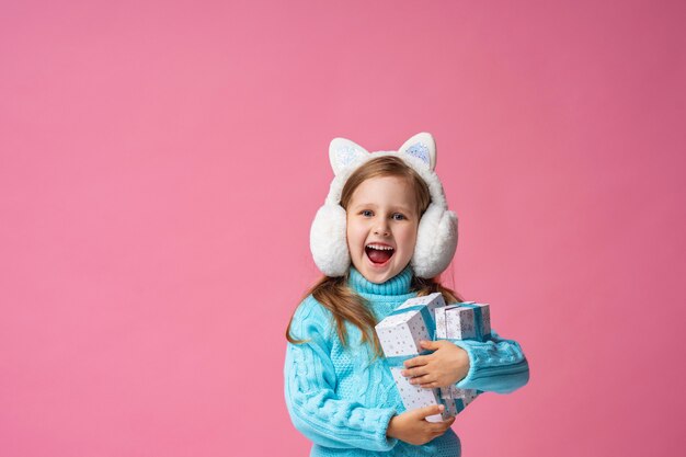 Little girl in fur headphones with gift boxes in her hands