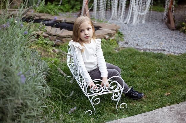 Little girl in the garden sitting on bench