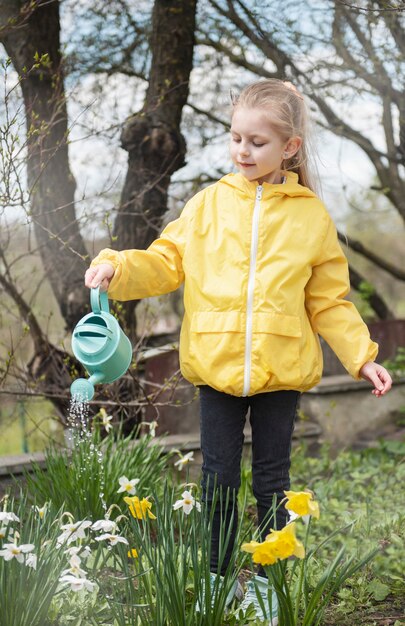 Little girl in a garden with green watering pot