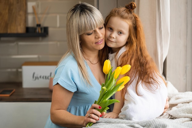 Little girl gave yellow tulips to her mother Woman loves her daughter