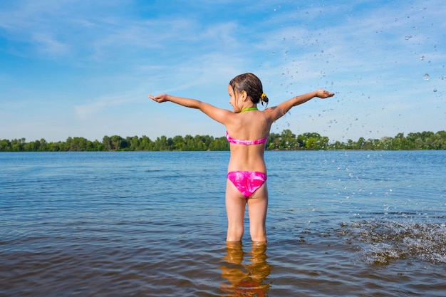 A little girl getting ready to swim in the river The opening of the beach season