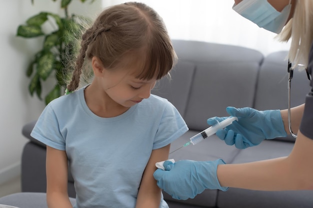 Little girl getting vaccination from pediatrician at medical office.