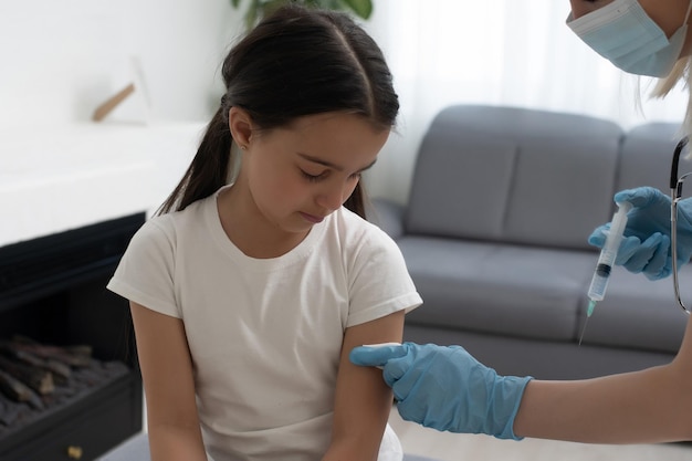 Маленькая девочка получает прививку от педиатра в медицинском кабинете.
