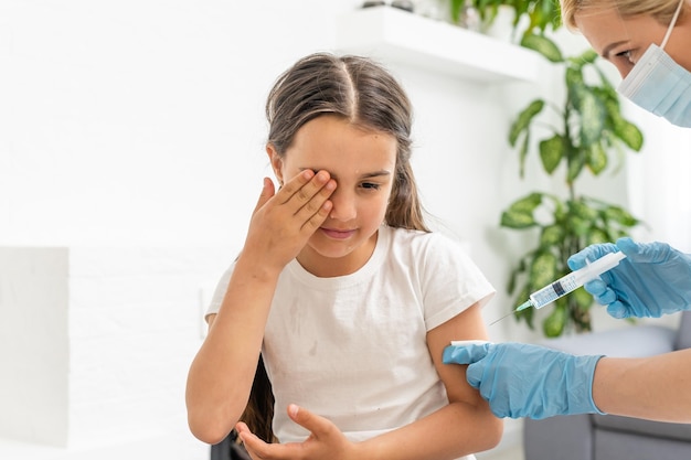 Little girl getting vaccination from pediatrician at medical office.