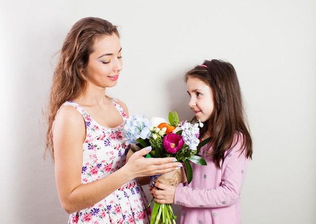 어린 소녀는 아름다운 엄마에게 다른 꽃의 꽃다발을 줍니다