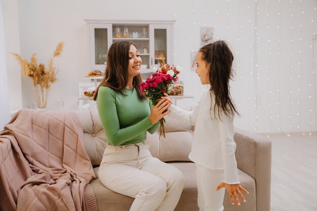 A little girl gives flowers to her mom for her birthday. mothers Day. bouquet of chrysanthemums