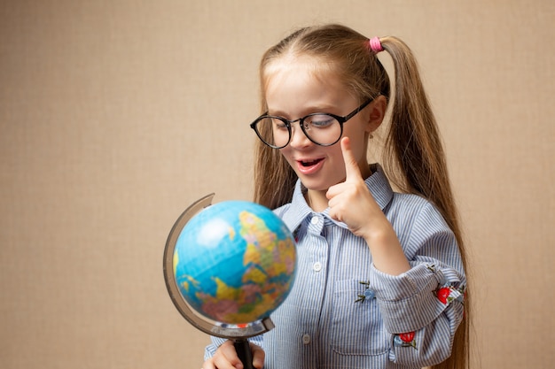 Little girl in glasses holding globe