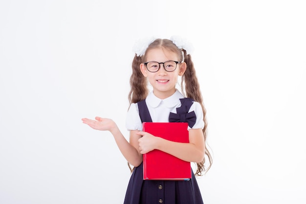 La bambina con gli occhiali e un'uniforme scolastica tiene un libro e un globo isolato su uno sfondo bianco