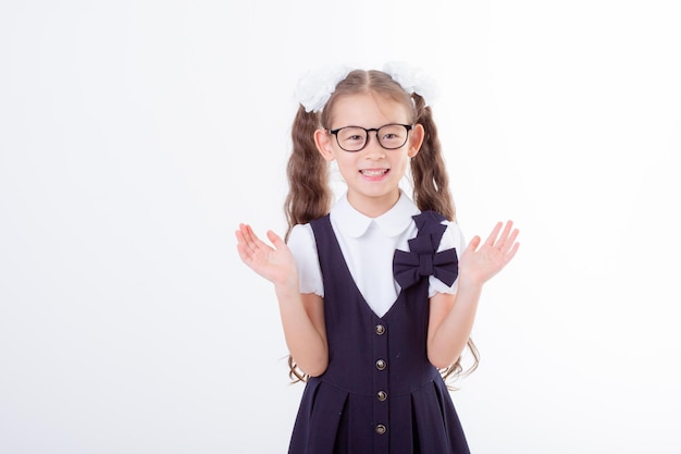 A little girl in glasses and a school uniform is isolated on a white background