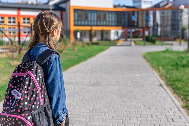 Little girl goes to the elementary school. Child with a backpack is going to study. Back to school concept.