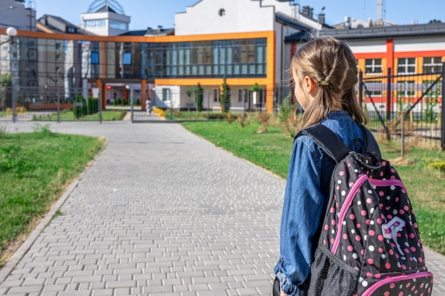 Little girl goes to the elementary school. Child with a backpack is going to study. Back to school concept.