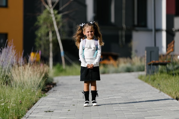 Una bambina va a scuola attraverso il parco lungo il sentiero. concetto di formazione a distanza. scolaretta