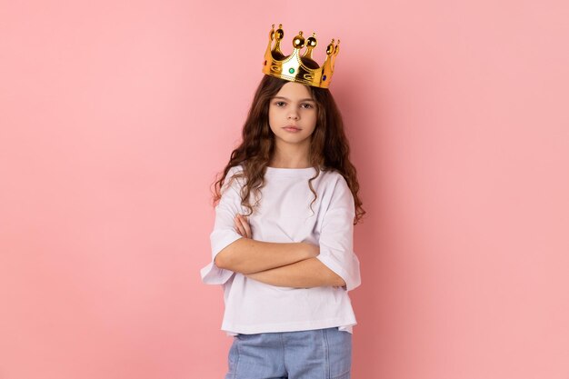 Little girl in golden crown keeping hands folded self confidence in success selfmotivation