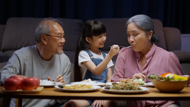 조부모와 함께 음식을 먹는 것을 즐기는 어린 소녀 손녀