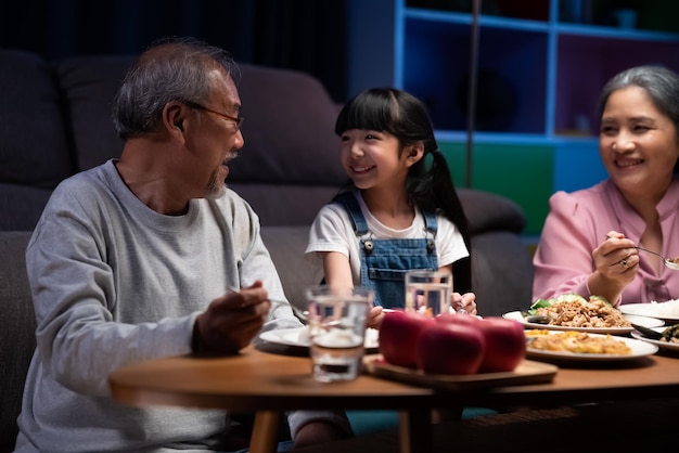 Little girl granddaughter enjoying to eat food with grandparents