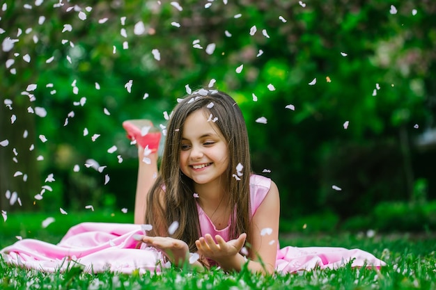 Little girl on green grass with petals