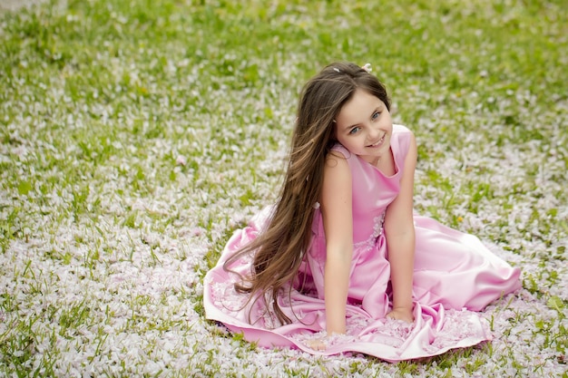Маленькая девочка на зеленой траве с лепестками