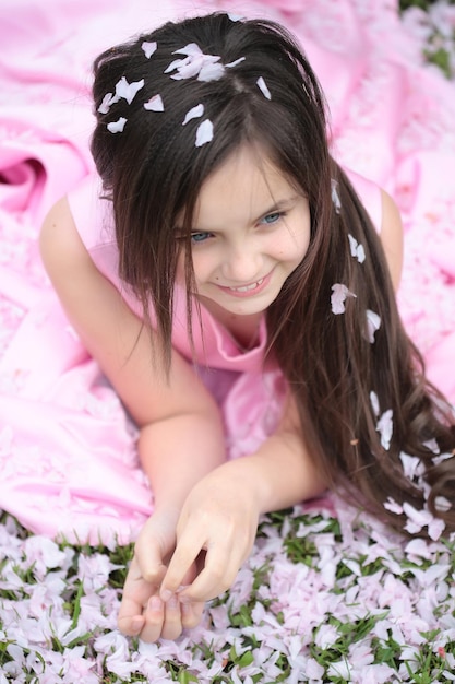 Little girl on green grass with petals