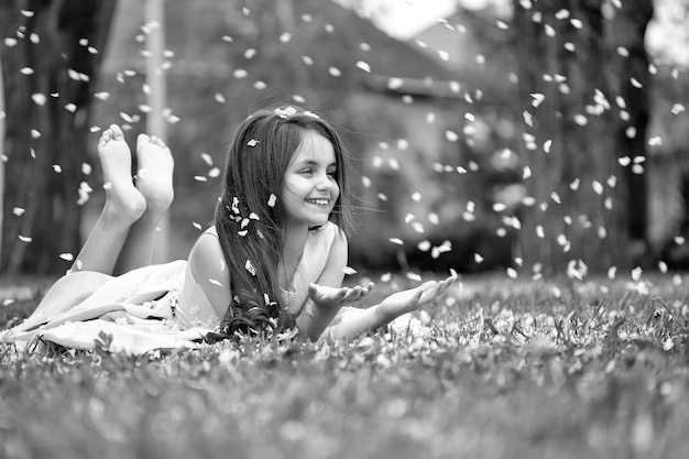 Little girl on green grass with petals