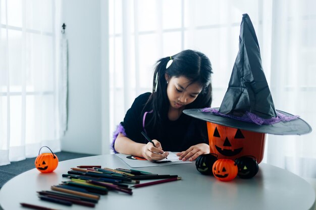 Маленькая девочка в костюме на Хэллоуин делает фонарь