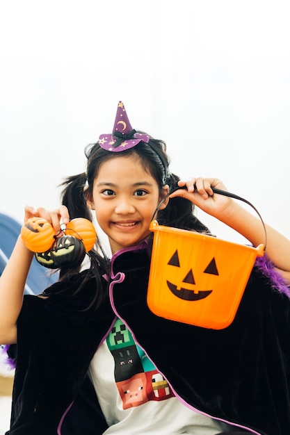 キャンディーとカボチャのバケツを持つハロウィーンの衣装を着た小さな女の子