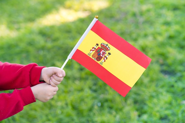 Le mani della bambina tengono la bandiera della spagna