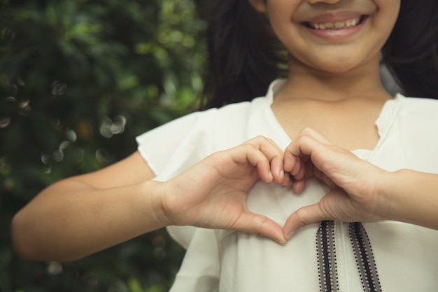 写真 白い背景の上のハートの形を作る小さな女の子の手