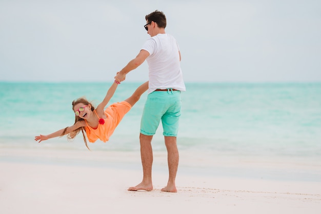 Little girl and happy dad having fun during beach vacation