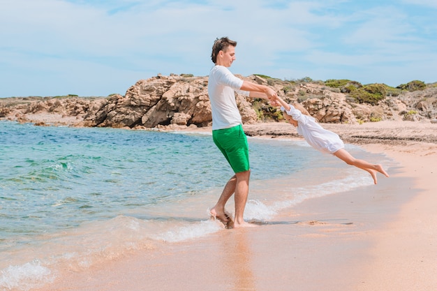 Little girl and happy dad having fun during beach vacation