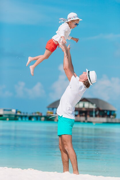 Little girl and happy dad having fun during beach vacation