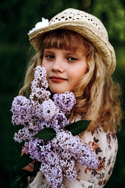 Little girl in a hat with flowers in the summer park