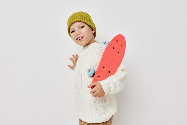 Little girl in hats with a skateboard in their hands light background