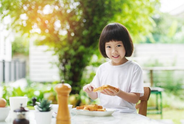 小さな女の子は朝食の幸せな時間を持っています