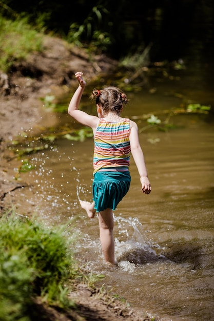 Little girl having a fun in the lake in the summer on a sunny day