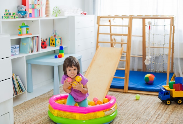 Little girl having fun riding a roller coaster on a wooden home sports gaming complex stairs