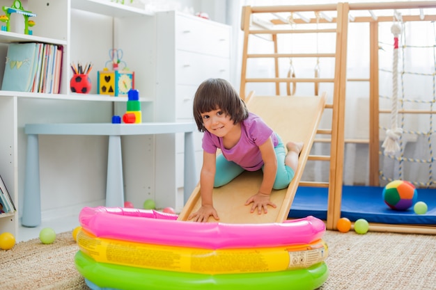 Little girl having fun riding a roller coaster on a wooden home\
sports gaming complex stairs