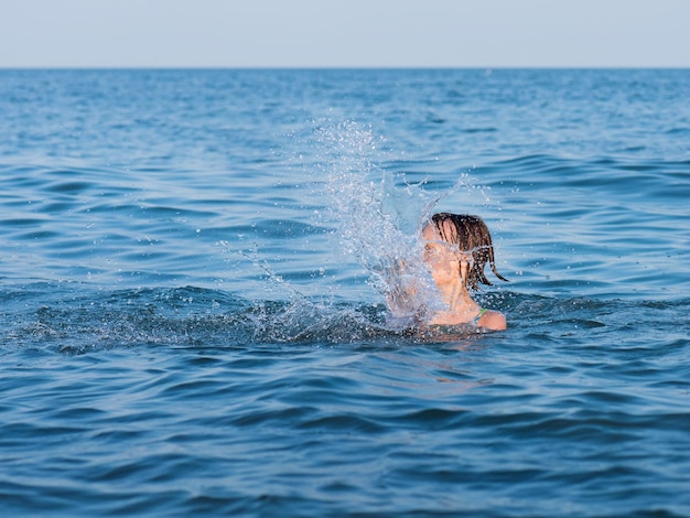 Little girl having fun in the sea with a lot of splashes on a sunny day