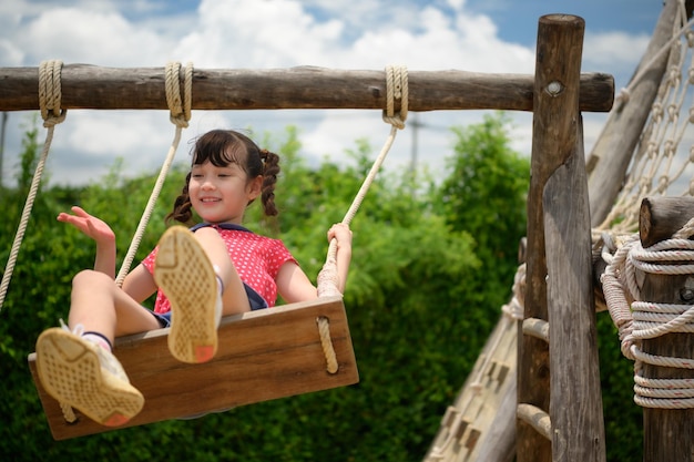 A little girl having fun swinging on a swing on a clear day