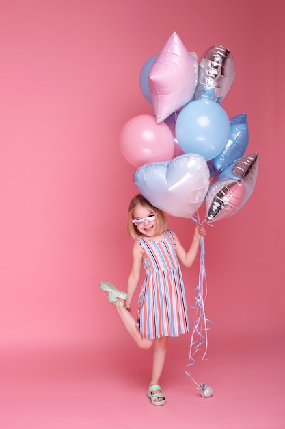 Little girl having fun with a bunch of bright balloons in the studio