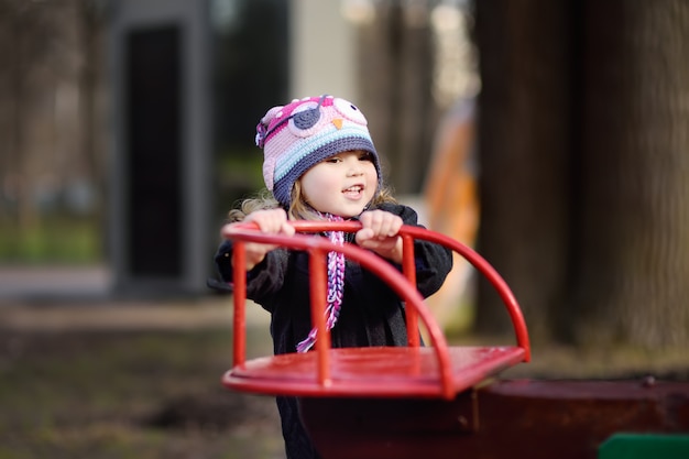 Bambina divertendosi con carosello sul parco giochi all'aperto