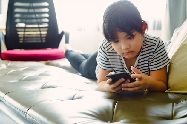 Little girl having fun with using smart phone at home