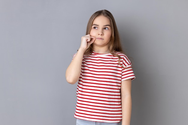 Little girl having mystery look making zip gesture to close mouth keeping secret zipping lips