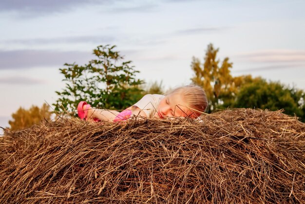 A little girl on the haystack in countryside