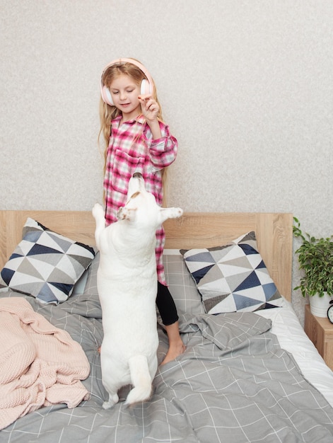 Little girl in headphones playing with her dog