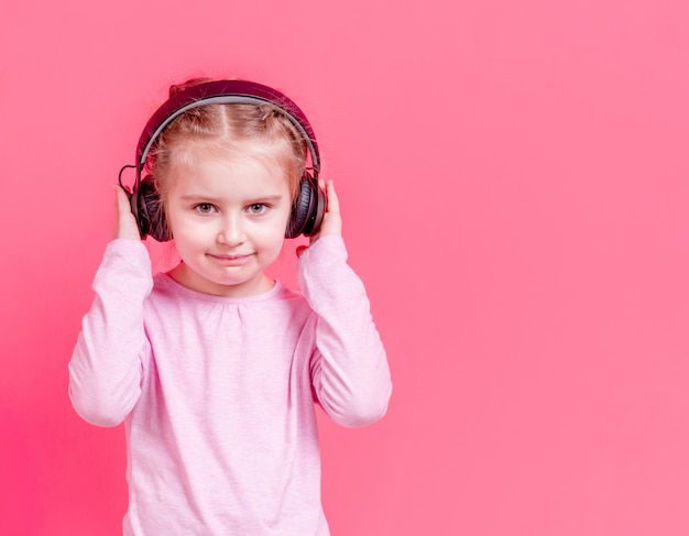 Little girl in headphones over rose background