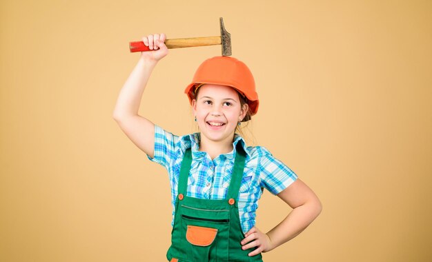 Little girl in helmet with hammer Kid worker in hat Labor day 1 may Foreman inspector Repair small girl repairing in workshop Safety expert Future profession building is not for everyone