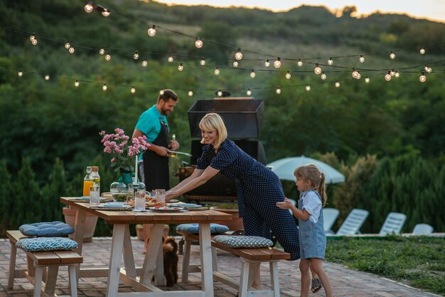 Foto bambina che aiuta la madre a sistemare il tavolo da pranzo nel cortile