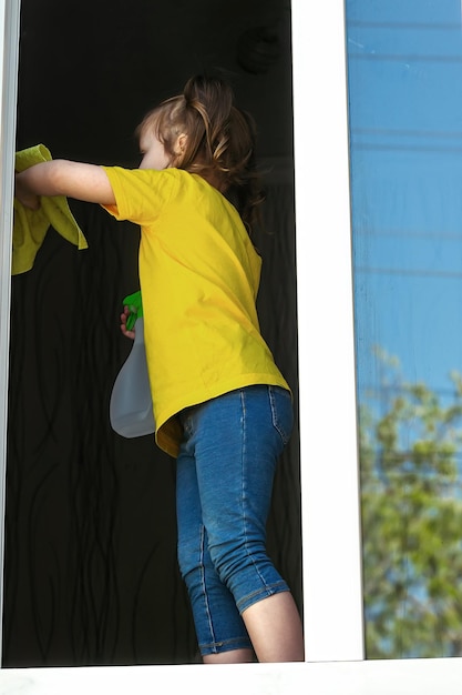 Little girl helps adults clean the window at home